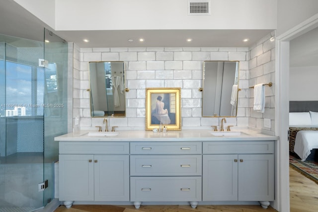 bathroom with decorative backsplash, vanity, and a shower with door