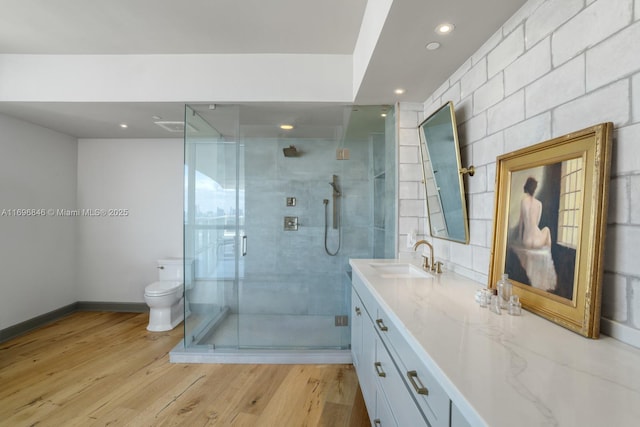 bathroom featuring hardwood / wood-style flooring, vanity, a shower with shower door, and toilet