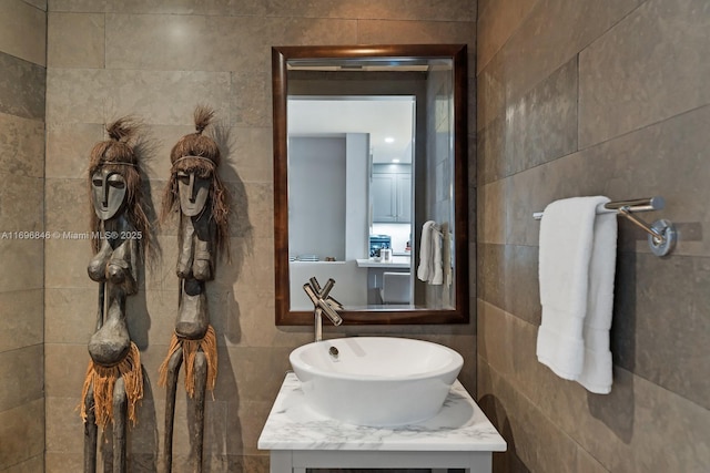 bathroom featuring vanity and tile walls