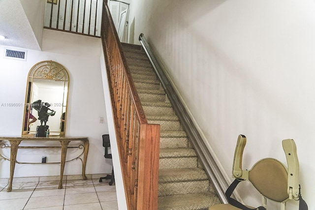 stairs featuring tile patterned floors and a high ceiling