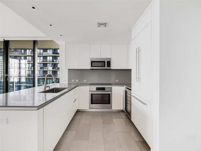 kitchen with sink, wine cooler, white cabinetry, kitchen peninsula, and stainless steel appliances