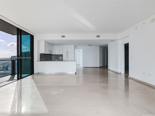 unfurnished living room featuring a wall of windows and sink