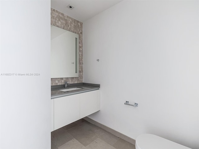 bathroom with vanity, toilet, and backsplash