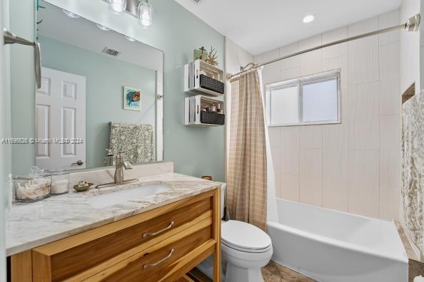 full bathroom featuring vanity, toilet, and shower / bathtub combination with curtain