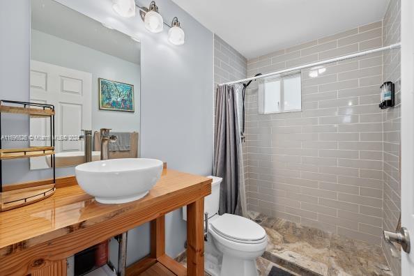 bathroom featuring toilet, sink, and a shower with shower curtain