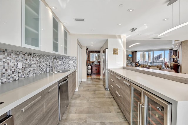 kitchen with appliances with stainless steel finishes, tasteful backsplash, sink, white cabinetry, and wine cooler