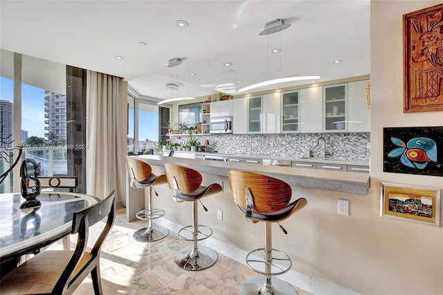 kitchen with white cabinets, sink, a breakfast bar area, and tasteful backsplash