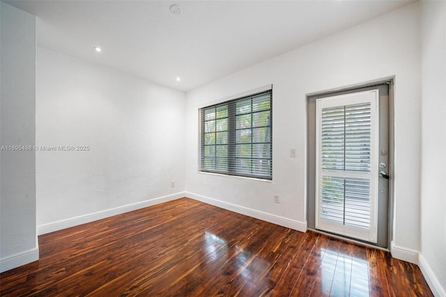 unfurnished room with baseboards, dark wood finished floors, and recessed lighting