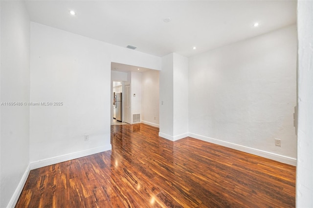 unfurnished room with recessed lighting, wood finished floors, visible vents, and baseboards