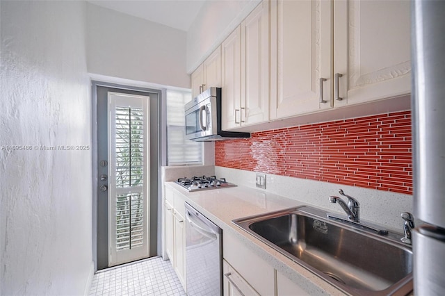 kitchen featuring stainless steel appliances, a sink, white cabinetry, light countertops, and tasteful backsplash