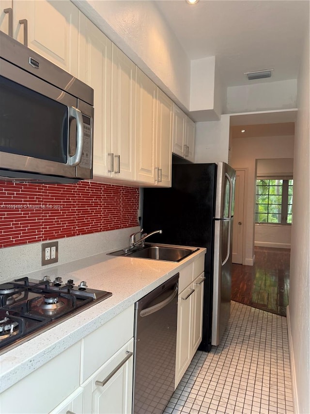 kitchen featuring backsplash, white cabinets, sink, light wood-type flooring, and appliances with stainless steel finishes