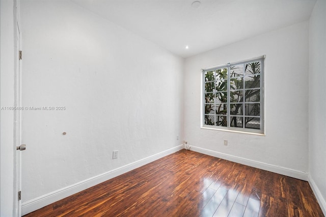 empty room with dark wood-style flooring and baseboards