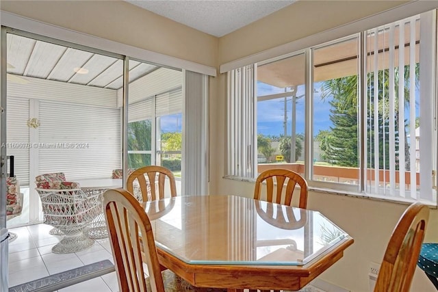 tiled dining room featuring a textured ceiling and a healthy amount of sunlight