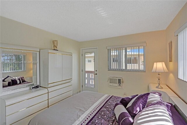 bedroom with a textured ceiling and an AC wall unit