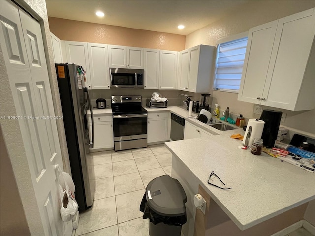 kitchen with kitchen peninsula, appliances with stainless steel finishes, and white cabinetry