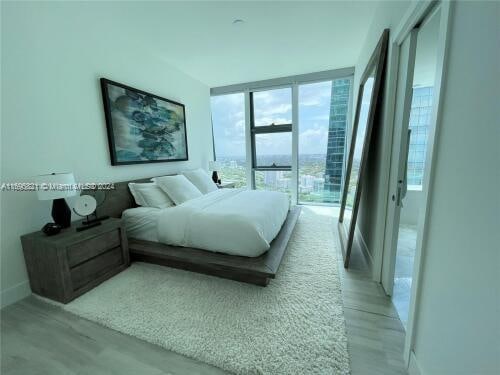 bedroom featuring a wall of windows and light hardwood / wood-style flooring