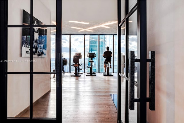 workout area with french doors, expansive windows, and hardwood / wood-style flooring