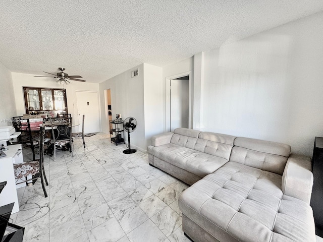 living room with ceiling fan and a textured ceiling