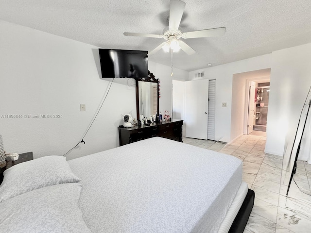 bedroom with ceiling fan, a textured ceiling, and connected bathroom