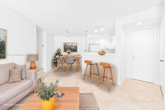 living area featuring light tile patterned floors, rail lighting, and baseboards