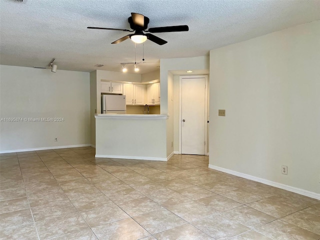 unfurnished living room with light tile patterned floors, a textured ceiling, ceiling fan, and sink