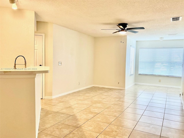 unfurnished room with light tile patterned floors, a textured ceiling, and ceiling fan