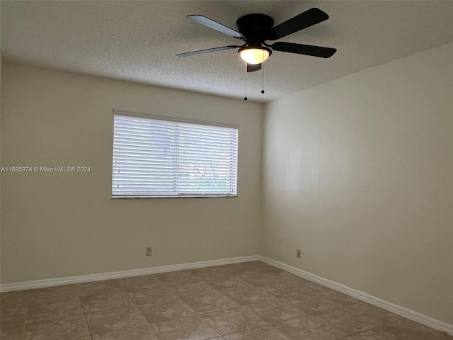 tiled empty room with ceiling fan and a textured ceiling