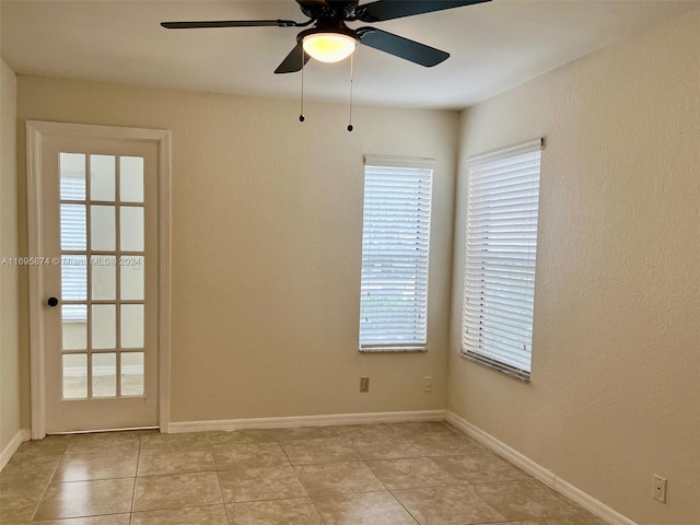 empty room with ceiling fan and light tile patterned floors