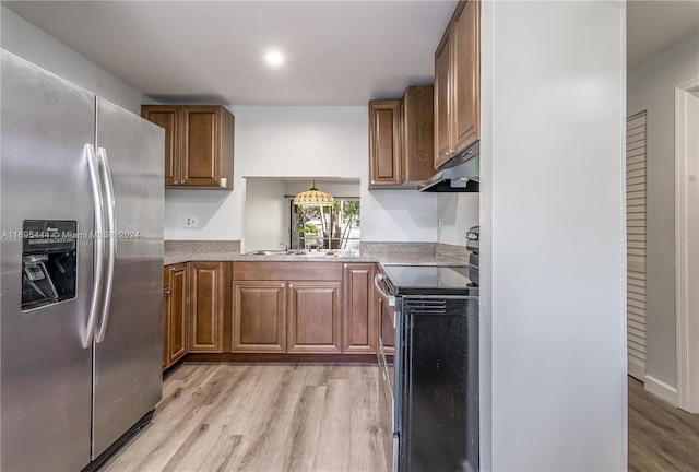 kitchen featuring black range with electric stovetop, stainless steel fridge, hanging light fixtures, and light wood-type flooring