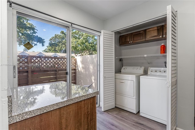 laundry room with washer and clothes dryer and light wood-type flooring