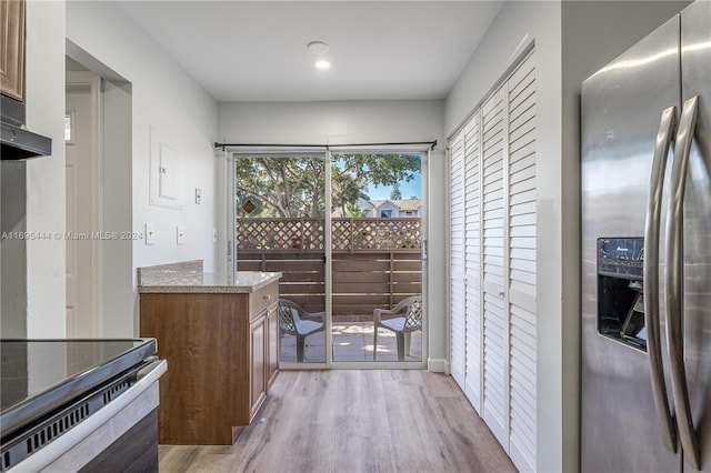 kitchen with electric range oven, light stone counters, light wood-type flooring, and stainless steel refrigerator with ice dispenser