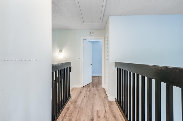 hallway with a textured ceiling and light hardwood / wood-style flooring