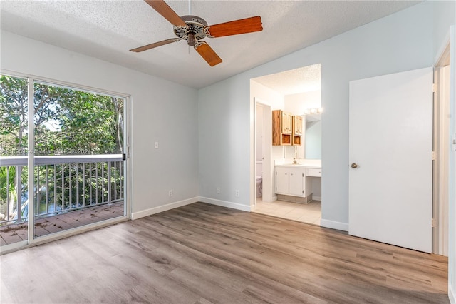 unfurnished bedroom with access to outside, ceiling fan, light wood-type flooring, a textured ceiling, and connected bathroom