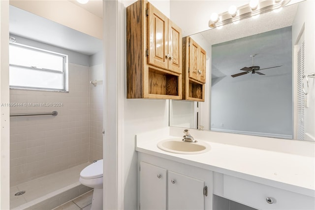 bathroom featuring vanity, tile patterned flooring, ceiling fan, toilet, and tiled shower