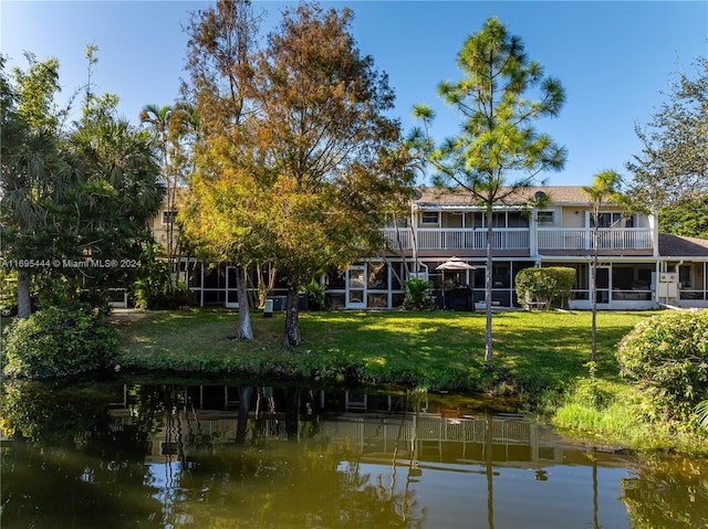 rear view of house featuring a lawn and a water view