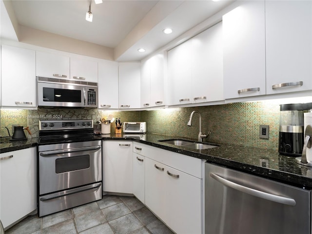 kitchen featuring decorative backsplash, appliances with stainless steel finishes, white cabinetry, and sink