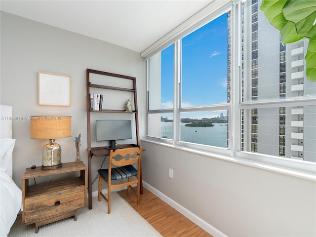 bedroom with a water view and hardwood / wood-style flooring