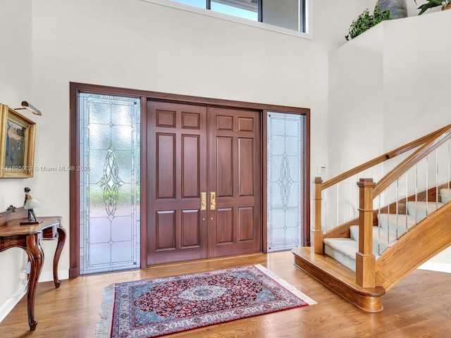 foyer featuring light hardwood / wood-style flooring, a towering ceiling, and a healthy amount of sunlight