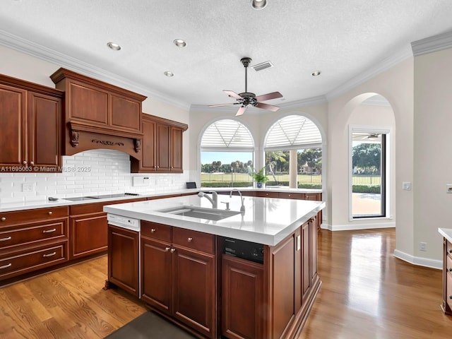 kitchen featuring light wood-type flooring, a textured ceiling, ceiling fan, a kitchen island with sink, and sink