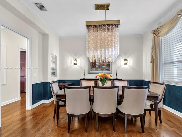 dining room featuring hardwood / wood-style floors, a chandelier, and ornamental molding