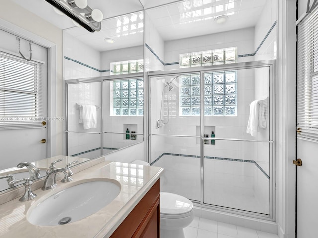 bathroom with tile patterned floors, vanity, toilet, and a shower with shower door