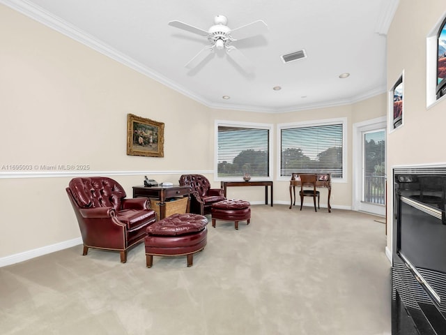 sitting room with ceiling fan, plenty of natural light, light colored carpet, and ornamental molding