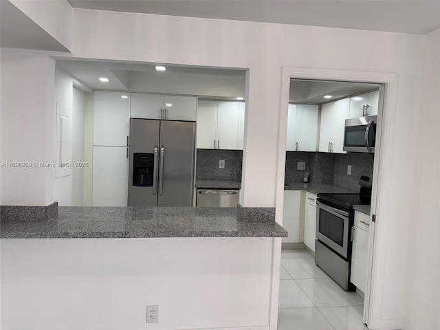 kitchen with light tile patterned floors, appliances with stainless steel finishes, decorative backsplash, and white cabinetry