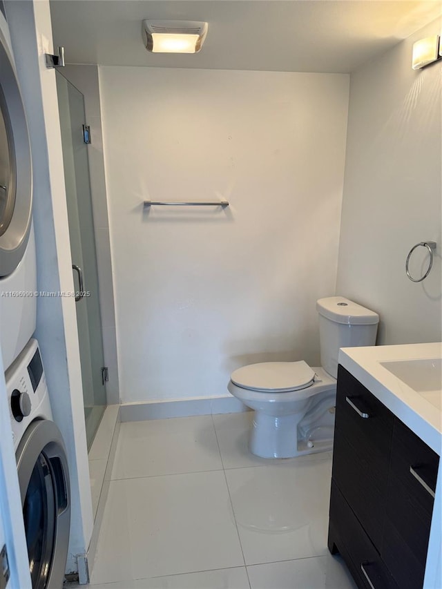 bathroom with toilet, vanity, tile patterned flooring, a shower with shower door, and stacked washer and clothes dryer