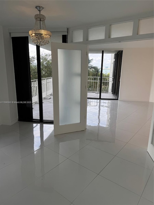 spare room featuring light tile patterned floors, a wealth of natural light, and a chandelier