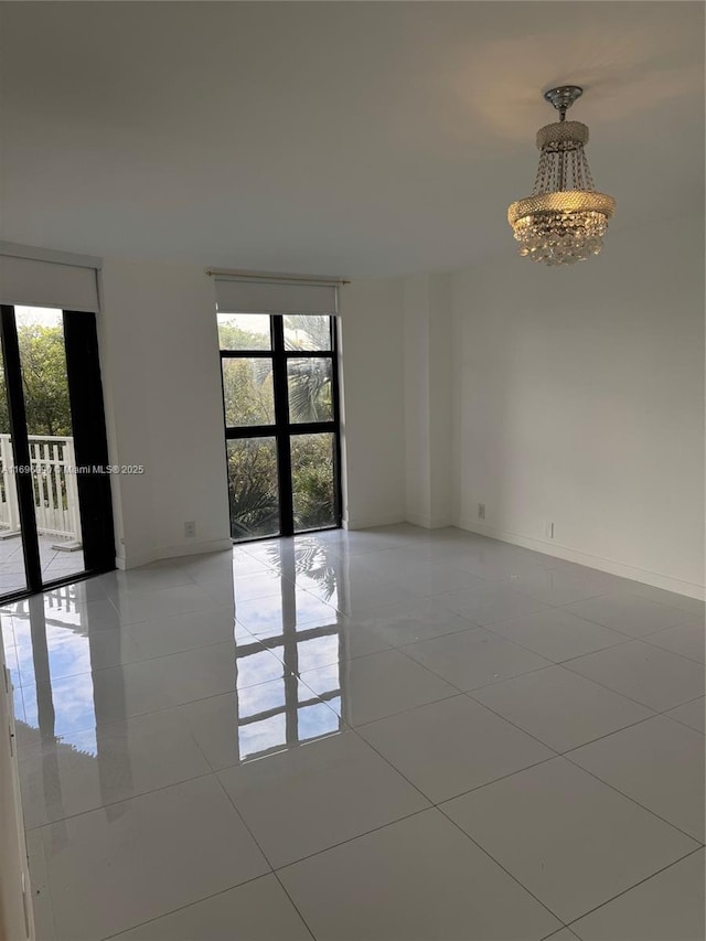 unfurnished room with a wealth of natural light, light tile patterned floors, french doors, and an inviting chandelier