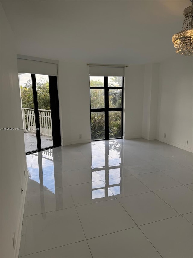 unfurnished room with light tile patterned floors, a healthy amount of sunlight, and a chandelier