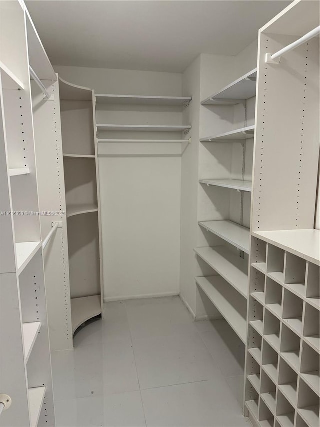 walk in closet with light tile patterned floors