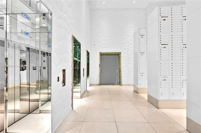 hallway featuring tile patterned flooring, a high ceiling, and a mail area