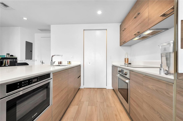 kitchen with sink, oven, light hardwood / wood-style floors, and black electric stovetop